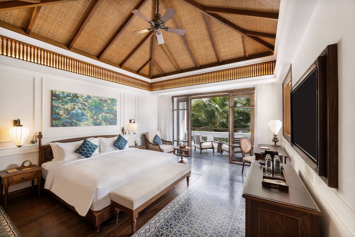 A spacious bedroom with a large bed, a ceiling fan, and a view of the outdoors through a sliding door.