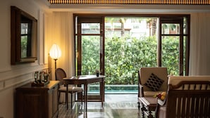 A room with a dining table, chairs, a sofa, and a lamp. There is a window with a view of greenery outside. - The Anam Mui Ne (Mui Ne)