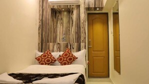 A bedroom with a bed, pillows, a wooden wall panel, an air conditioning unit, and a door. - Hotel Golden Inn (Mumbai)
