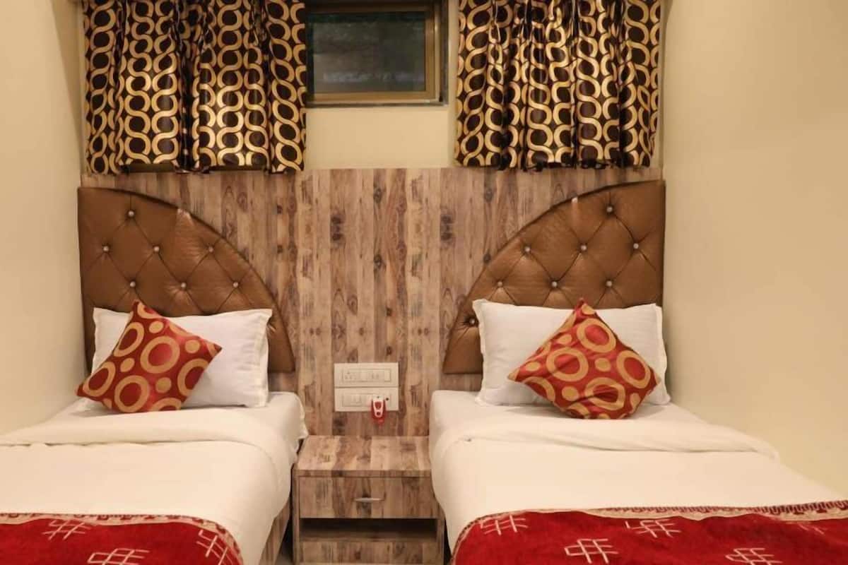 A double bed with a wooden headboard, two pillows, and a red blanket.