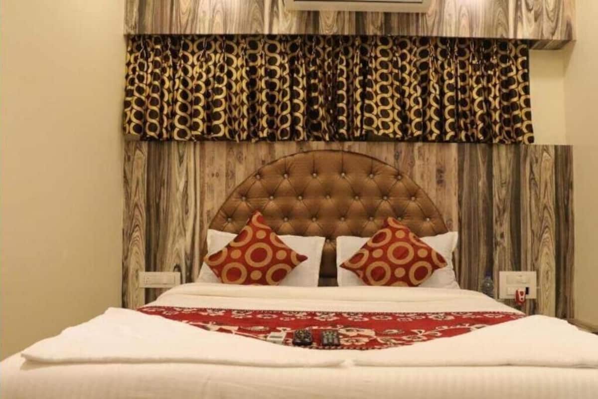 A bedroom with a tufted headboard, patterned curtains, and a decorative bedspread.