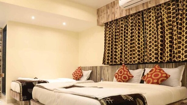 A modern hotel room with a large bed, two bedside tables, and a patterned headboard. - Hotel Golden Inn (Mumbai)