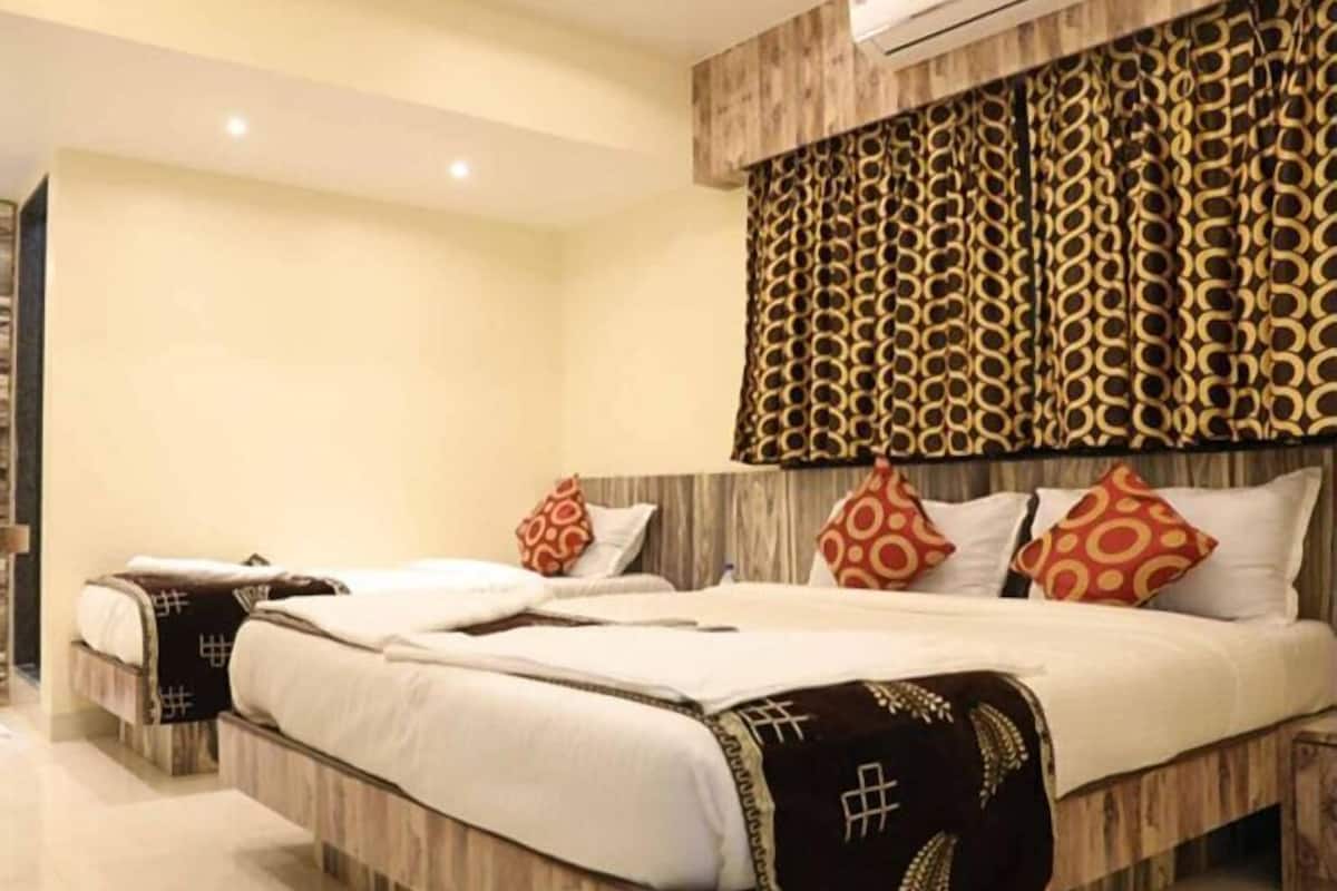 A modern hotel room with a large bed, two bedside tables, and a patterned headboard.