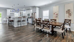 A modern kitchen with white cabinets, a central island, and bar stools. - 4BR Spacious Retreat • Walk to Beach • Pets OK (Norfolk)