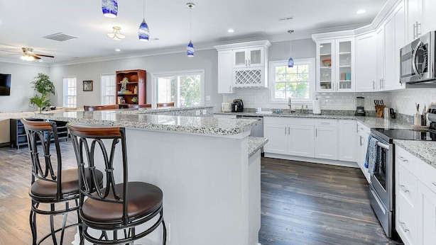 A spacious kitchen with white cabinets, a granite countertop, and blue pendant lights. - 4BR Spacious Retreat • Walk to Beach • Pets OK (Norfolk)