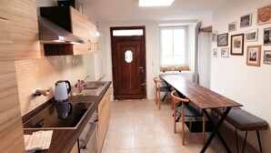 A compact kitchen with a wooden countertop, a built-in stove, a sink, and a dining table with chairs.