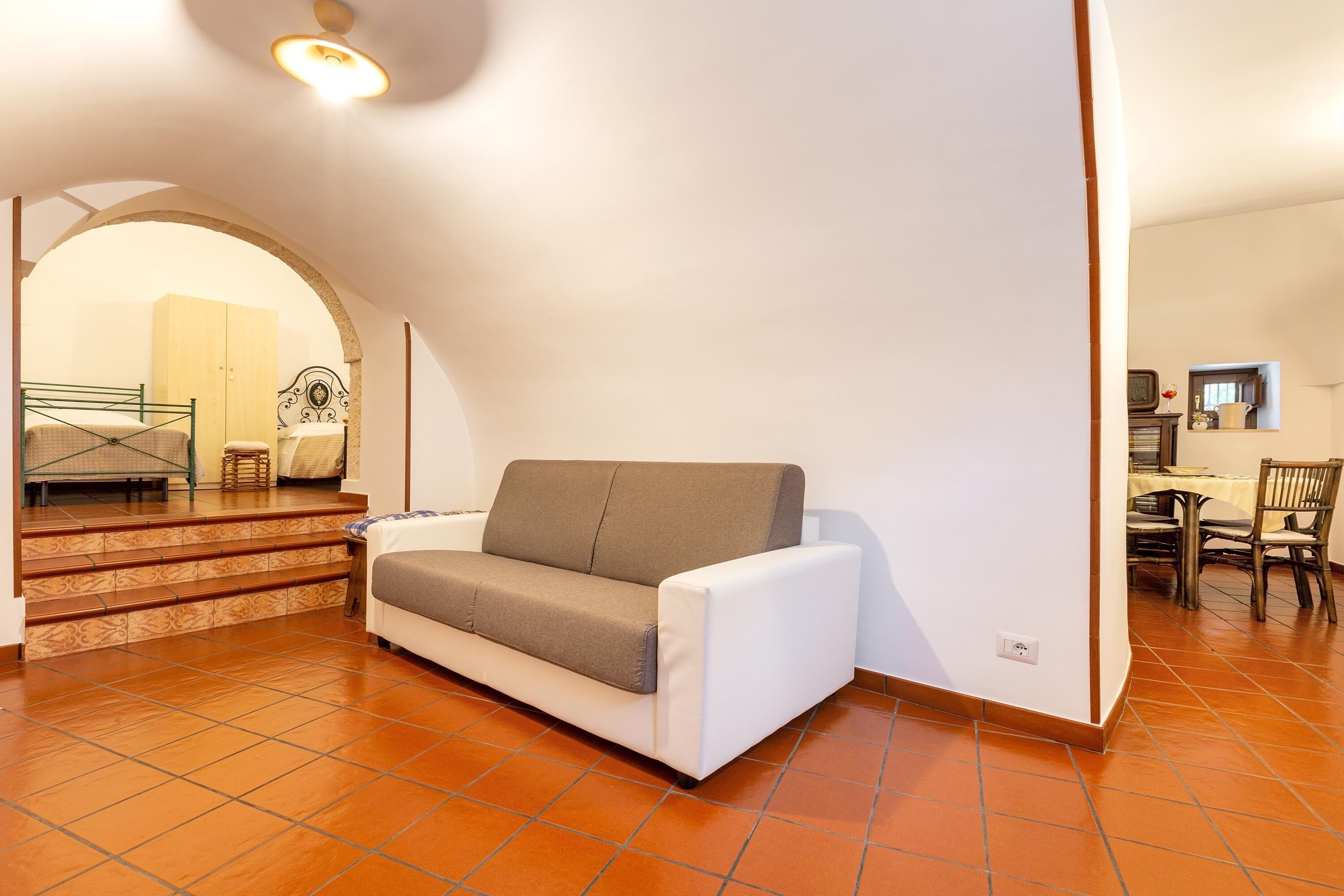 Un salon moderne avec un canapé, un coin repas comprenant une table et des chaises, et un escalier menant à une autre pièce.