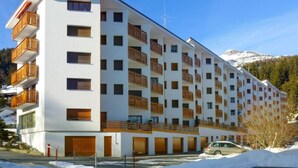 Ett hotell med flera våningar och balkonger, en skidlift i bakgrunden och ett snötäckt landskap.