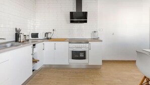 Eine moderne Küche mit weißen Schränken, einem eingebauten Backofen, einer Mikrowelle und einer schwarzen Dunstabzugshaube.