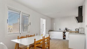 Eine moderne Küche mit weißen Schränken, einem Holzespeisetisch und einem Fenster mit Jalousien.