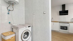 Ein Waschraum mit Waschmaschine, Wäscheständer und Warmwasserbereiter.