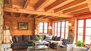 A cozy log cabin interior with a wooden ceiling, a sofa set, a coffee table, and a chair. - Lindefjeldbu by Interhome (Eikerapen)