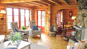 A cozy log cabin interior with wooden floors, a stone fireplace, and a dining area. - Lindefjeldbu by Interhome (Eikerapen)