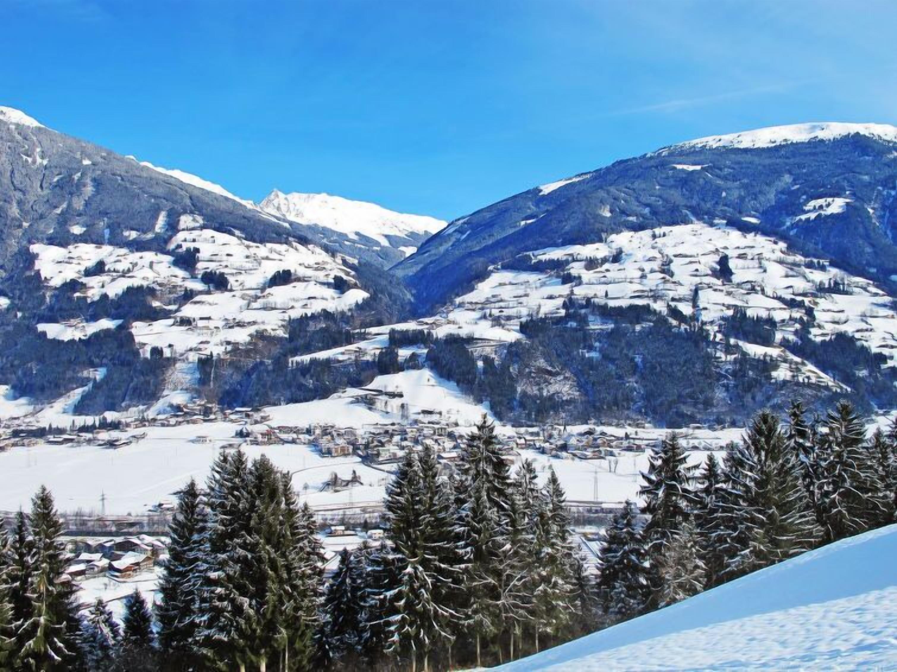 Un paysage montagneux enneigé, avec une ville nichée au fond de la vallée.