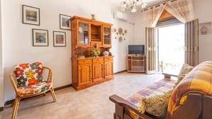 A living room with a sofa, a patterned chair, a wooden cabinet, and a television. - 3032 Casa di Ada by Barbarhouse (Manduria)