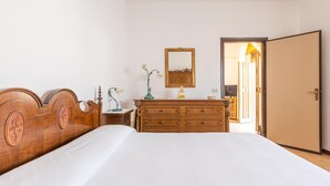 A bedroom with a wooden bed, a dresser, a mirror, and a door leading to another room. - 3032 Casa di Ada by Barbarhouse (Manduria)