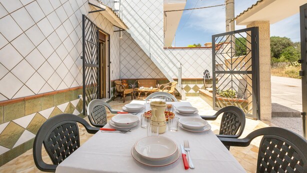 An outdoor dining area with a table set for four, surrounded by chairs, and a view of a building with a tiled facade. - 3032 Casa di Ada by Barbarhouse (Manduria)