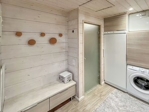 A laundry room with a washing machine, a dryer, and a bench with a box on it. - Villa paadar by Interhome (Inari)