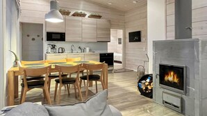 A modern kitchen with wooden cabinets, a dining area with a table and chairs, and a wood-burning stove. - Villa paadar by Interhome (Inari)