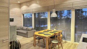 A modern interior with a wooden dining table, chairs, a sofa, and large windows with blinds. - Villa paadar by Interhome (Inari)