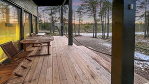 A wooden deck with a table and chairs, overlooking a forested area. - Villa paadar by Interhome (Inari)
