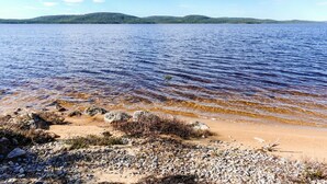 A beach with clear water, pebbles, and distant hills. - Villa paadar by Interhome (Inari)