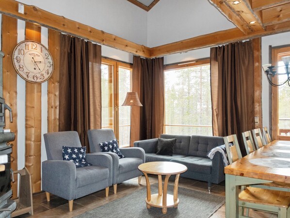 A cozy room with a wooden ceiling, a large clock, and a dining area with a table and chairs.