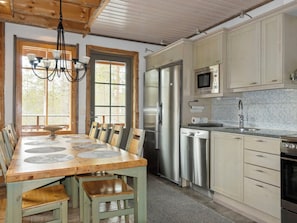 Een moderne keuken met een houten eettafel, roestvrijstalen apparatuur en uitzicht op de omgeving.