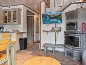 A living room with a television, a fireplace, and a kitchen area.