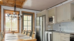 A modern kitchen with wooden cabinets, stainless steel appliances, and a dining area with a wooden table and chairs.