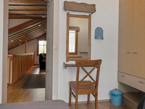Une pièce avec une chaise en bois, une poubelle bleue et un meuble en bois.
