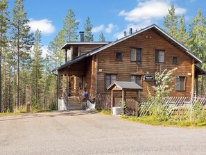 Une cabane en bois avec un porche, un garage et une cour clôturée.