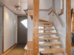 Een houten trap met een leuning, een bankje onderaan en een deur aan de bovenkant.