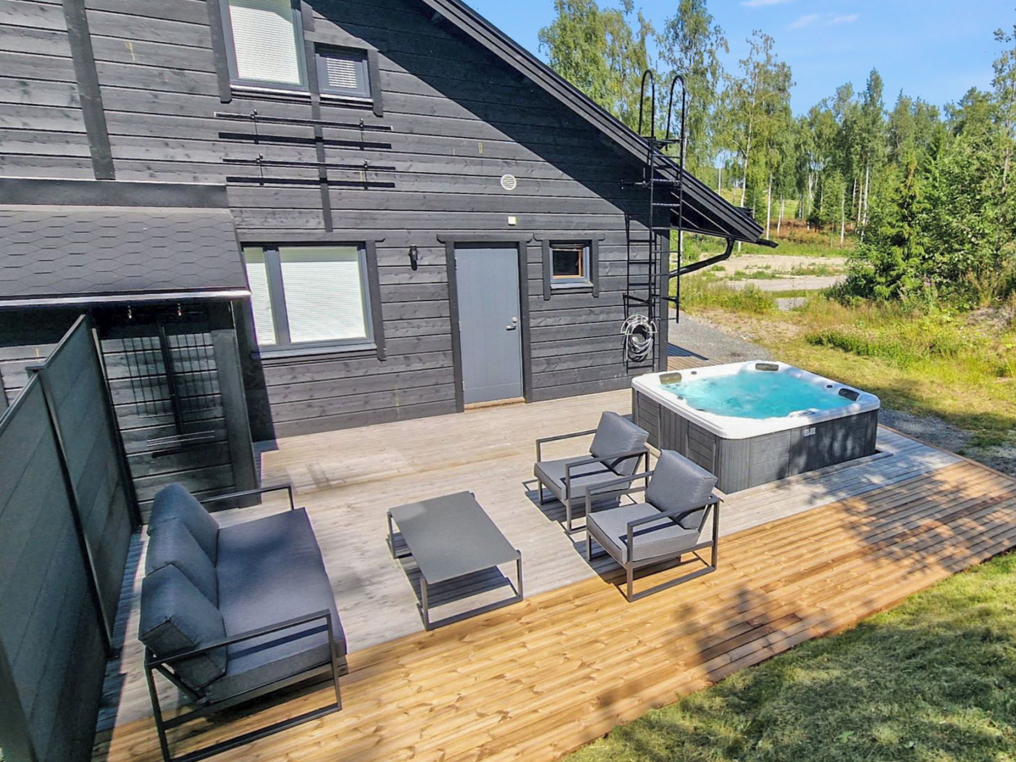 Une maison moderne dotée d’une terrasse, d’un jacuzzi et d’un espace salon extérieur.