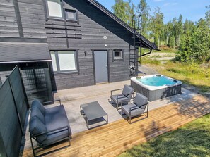 Ein modernes Haus mit einer Terrasse, einem Whirlpool und Sitzmöglichkeiten im Freien.