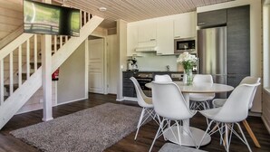 Una cucina moderna con mobili bianchi, un frigorifero in acciaio inossidabile e una zona pranzo con sedie e tavolo bianchi.