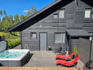 Une maison moderne dotée d’un jacuzzi, d’un espace salon extérieur et d’une terrasse.