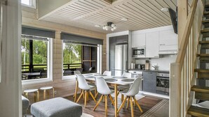 Una cocina moderna con armarios blancos, electrodomésticos de acero inoxidable y una escalera de madera.