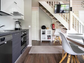 A modern kitchen with a built-in oven, a coffee machine, and a dining area with a white table and chairs. - Himoksen keiju 1 by Interhome (Kuhmoinen)