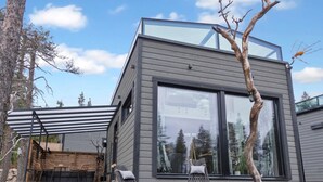 A modern house with a large glass window, a wooden deck, and two lounge chairs. - Levi secret igloo revontuli 10d by Interhome (Kittilä)