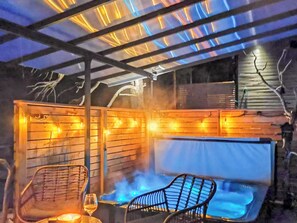 Un espace extérieur aménagé avec des sièges chauffants, comprenant un banc et des chaises en bois, une table en verre et une vue sur une piscine.