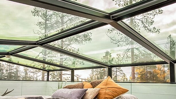 A bedroom with a large skylight, a bed with multiple pillows, and a view of trees outside. - Levi secret igloo revontuli 10d by Interhome (Kittilä)