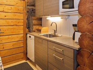 Una cocina compacta con armarios de madera, un lavamanos de acero inoxidable y un microondas.