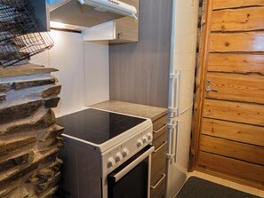 Una cocina con estufa, horno y puerta de madera.