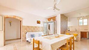 A dining area with a table set for four, a kitchen in the background, and a ceiling fan. - 2907 Casa la Terrazza by Barbarhouse (Manduria)
