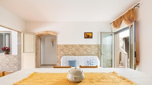 A room with a bed, a table with a pot, a window, and a door. - 2907 Casa la Terrazza by Barbarhouse (Manduria)