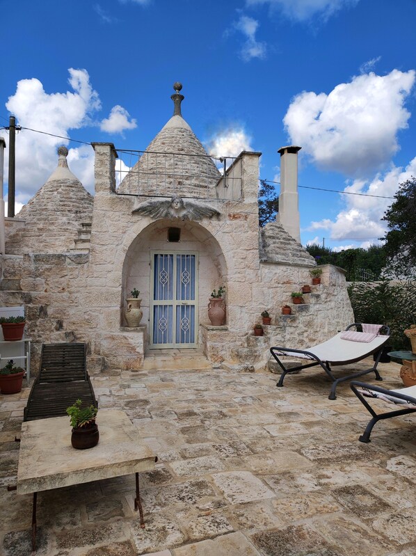 Il s’agit d’un bâtiment en pierre, doté d’un toit conique, d’une entrée centrale en arc de cercle et d’une cheminée. On y trouve des plantes en pot et du mobilier d’extérieur.