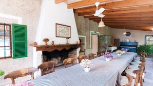 A dining area with a long table, wooden chairs, a fireplace, and a ceiling fan. - Apartment 1 bedroom (Sineu)