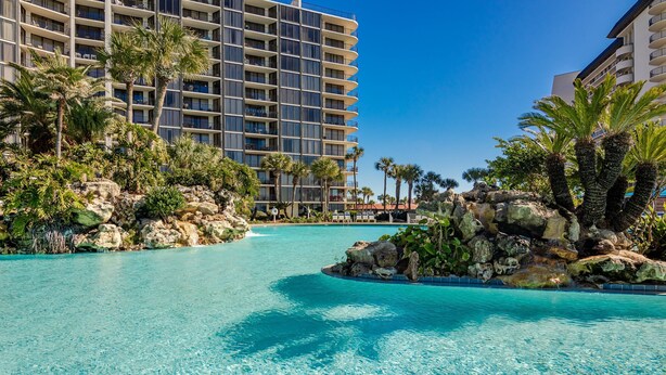 Ein Hotel mit großem Pool, umgeben von Palmen und Felsen.