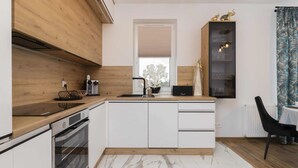 A modern kitchen with wooden cabinetry, a built-in oven, and a marble countertop.
